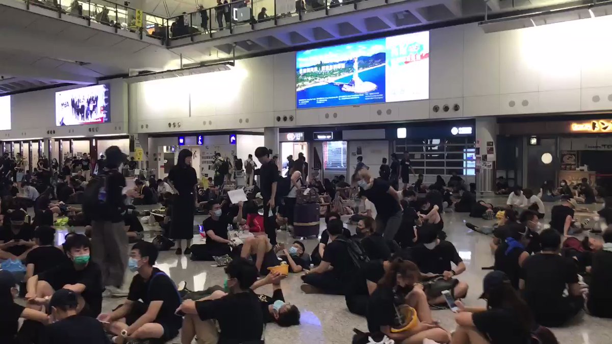 Many protesters are still here at the Hong Kong Airport, chanting Black policemen, return an eye, after local media reported that a female protester was shot in the eye last night by rubber bullets at Tsim Sha Tsui. All flights have been cancelled.
