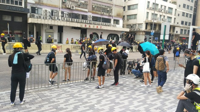 Protesters in Ngau Tau Kok are dismantling street fences to build barricades, while officers have formed a line of defence outside the police station.  #HongKongProtests