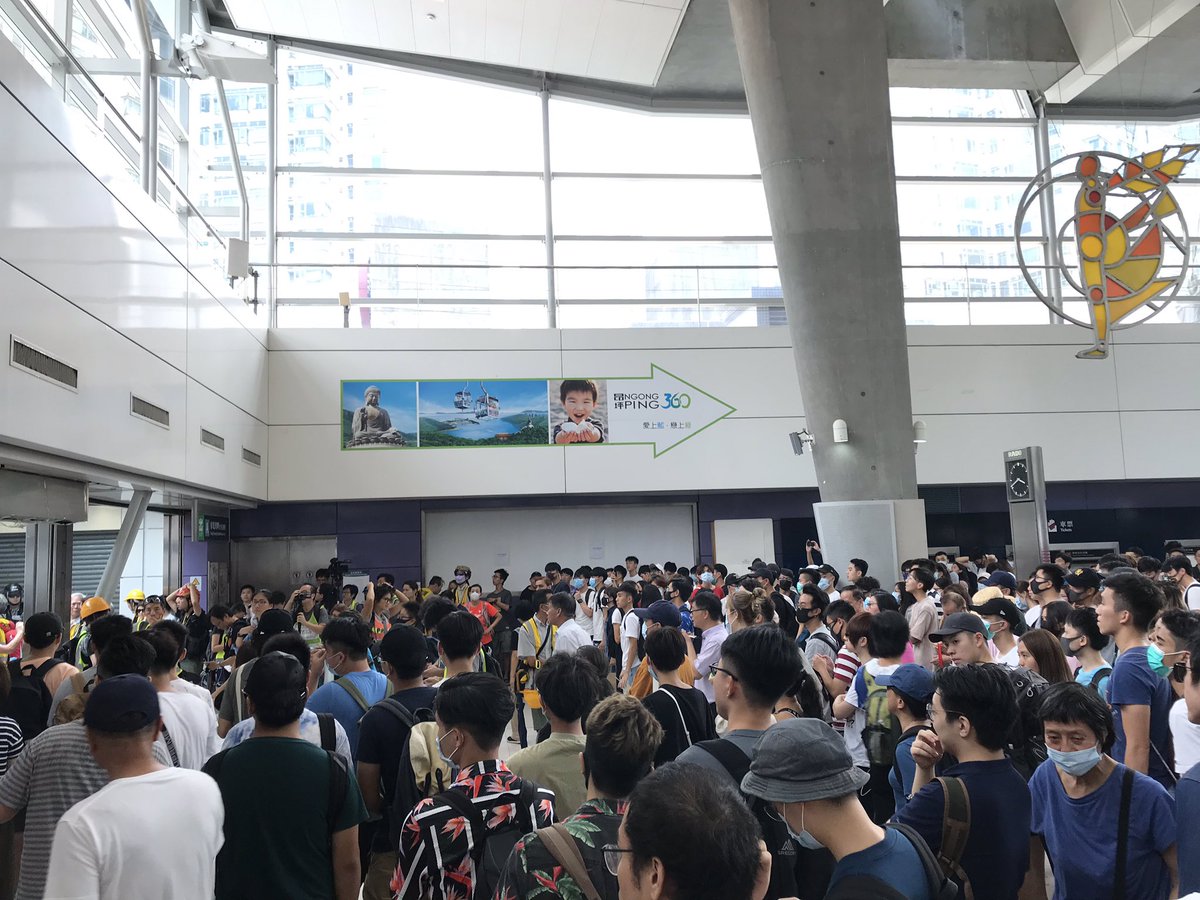 In Tung Chung MTR station a standoff between passengers and riot police forming a line outside is beginning to dissipate as people get back on the trains to move elsewhere on the rail network. #HKprotests