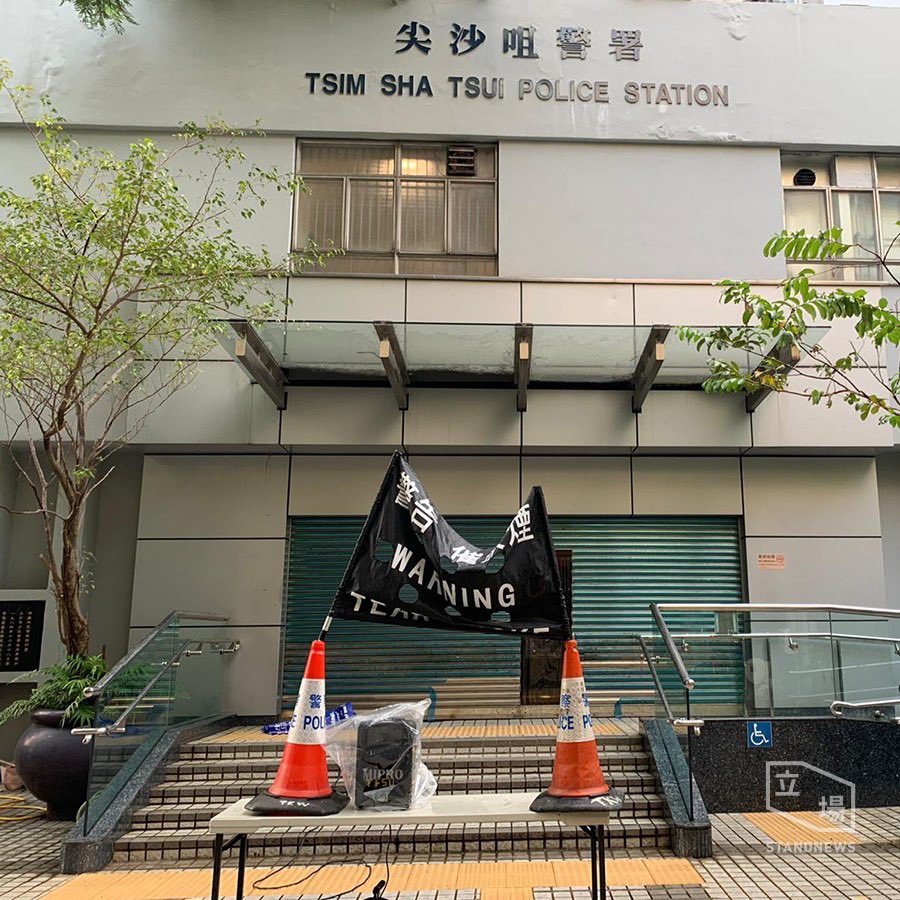 From ⁦@StandNewsHK⁩, black flag warning of tear smoke is put up on traffic cones to the marching crowd in Tsim Sha Tsui.