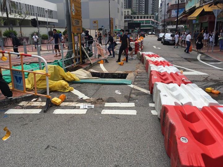 Protesters set up makeshift roadblocks and graffitied a Maxim's restaurant in Tsuen Wan on Sunday. Police vehicles drove with their doors open to facilitate quick arrests. Photo: United Social Press.