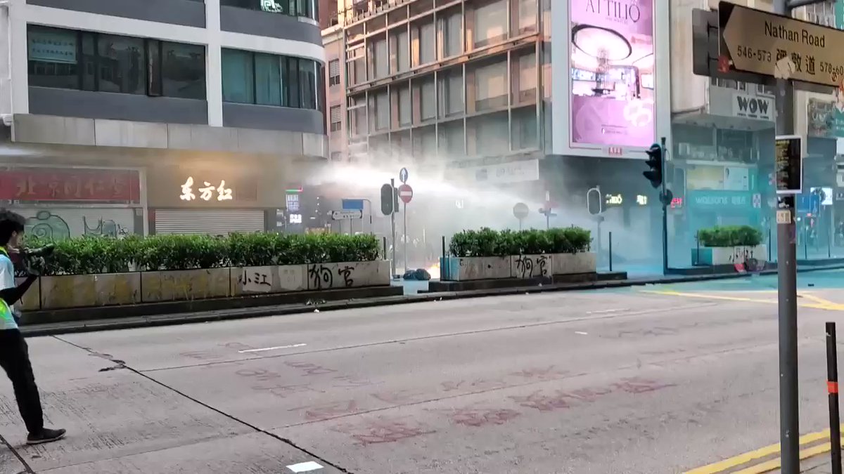 The water cannon truck firing water and blue liquid while pushing up at a relatively high speed on Nathan Road. Reporters on the frontlines can be seen scurrying away, while protesters are nowhere to be seen.  