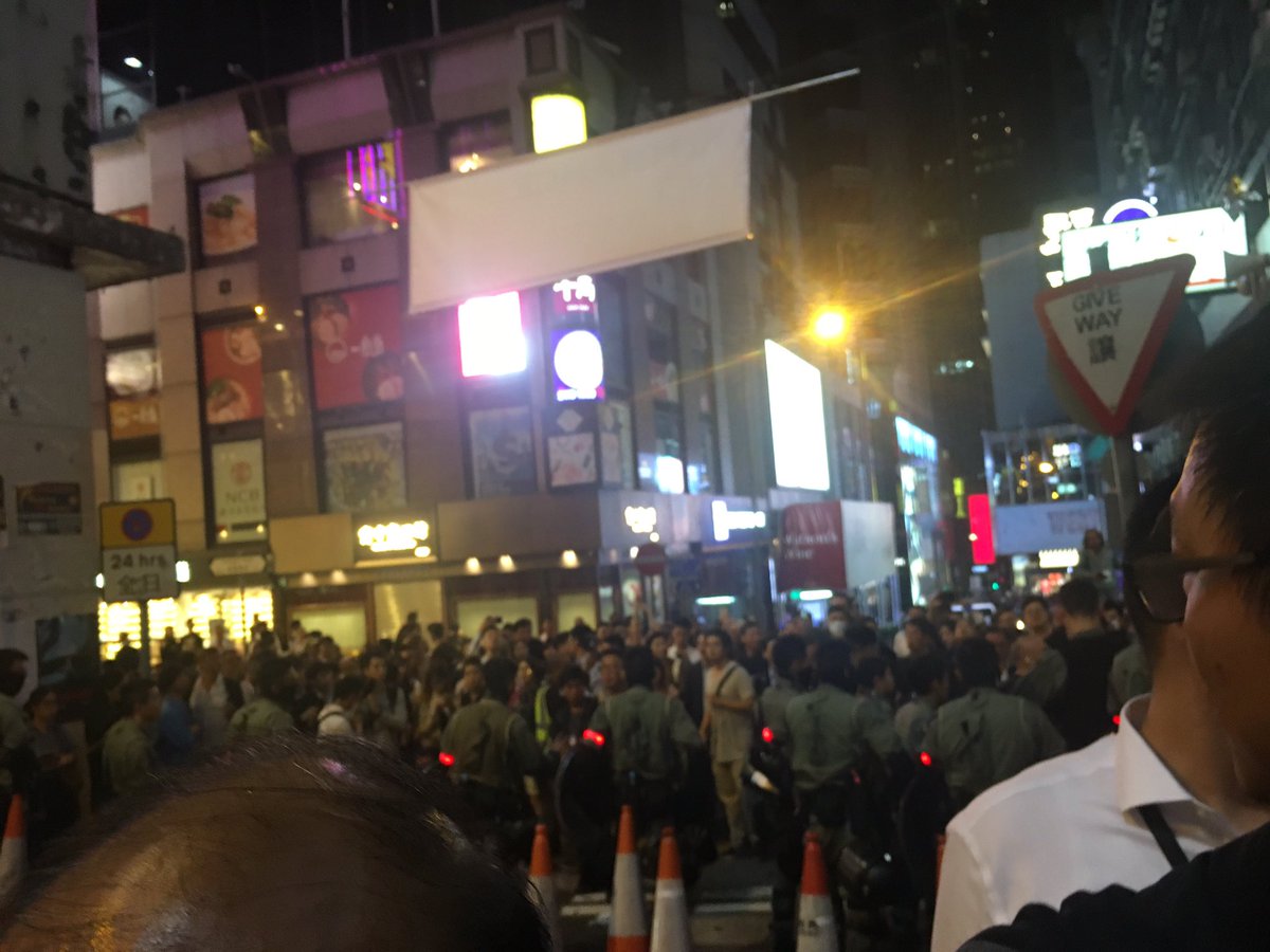 A line of marshals and riot police, whose faces were covered by black bandanas, have blocked off the one-way sloped entrance to bars in Lan Kwai Fong. This was met by jeers of revelers in Halloween costumes who shouted anti-police slogans