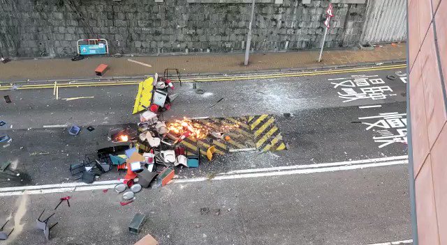 Five to six protesters remaining at a footbridge from HKU to the MTR station throw shattered glass, stones and chairs onto Pok Fu Lam Rd, as well as several petrol bombs as roadblocks.  Video: SCMP/Karen Zhang