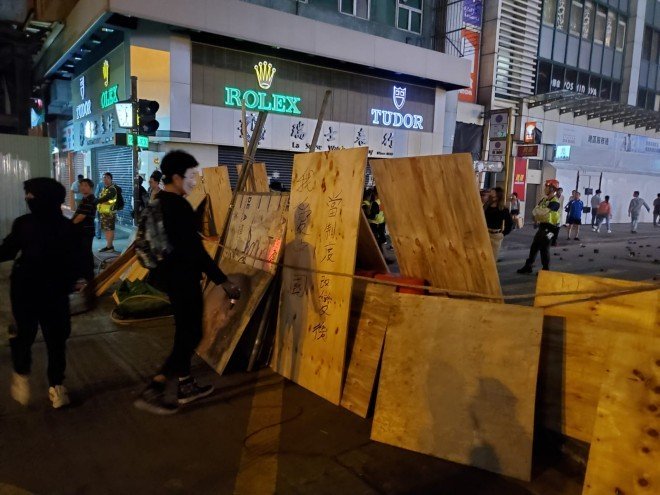 Protesters are extending the blockade on Nathan Road in Mong Kok. A spray-paint message on a wood board reads: When the system is changed, I will love China.  